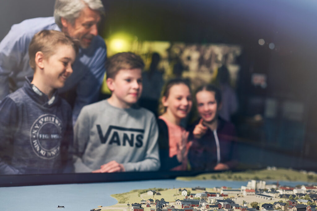 Lapset ja mies katsovat pienoismallia kaupungista.