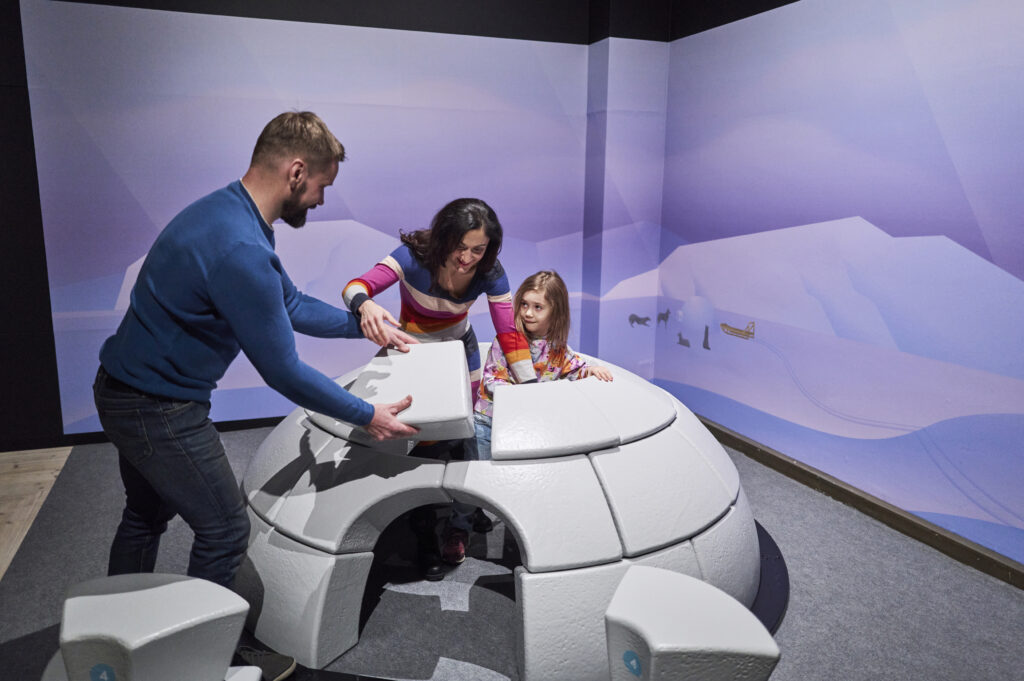 Lapsi ja kaksi aikuista rakentaa iglua tiedekeskuksessa.