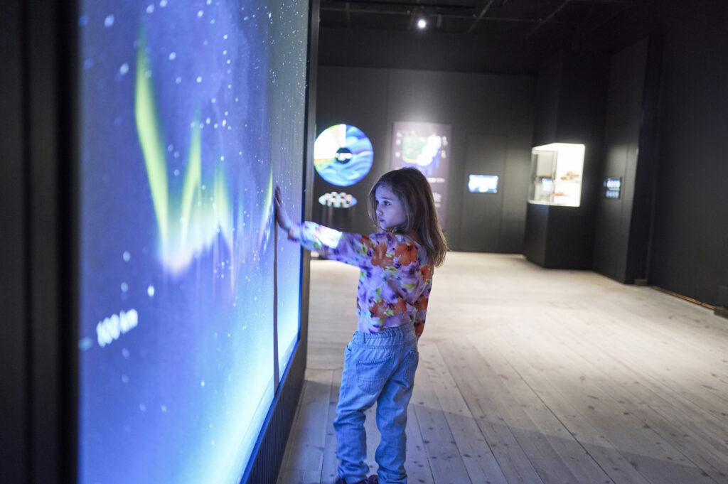 Lapsi piirtää kädellään seinään revontulia.