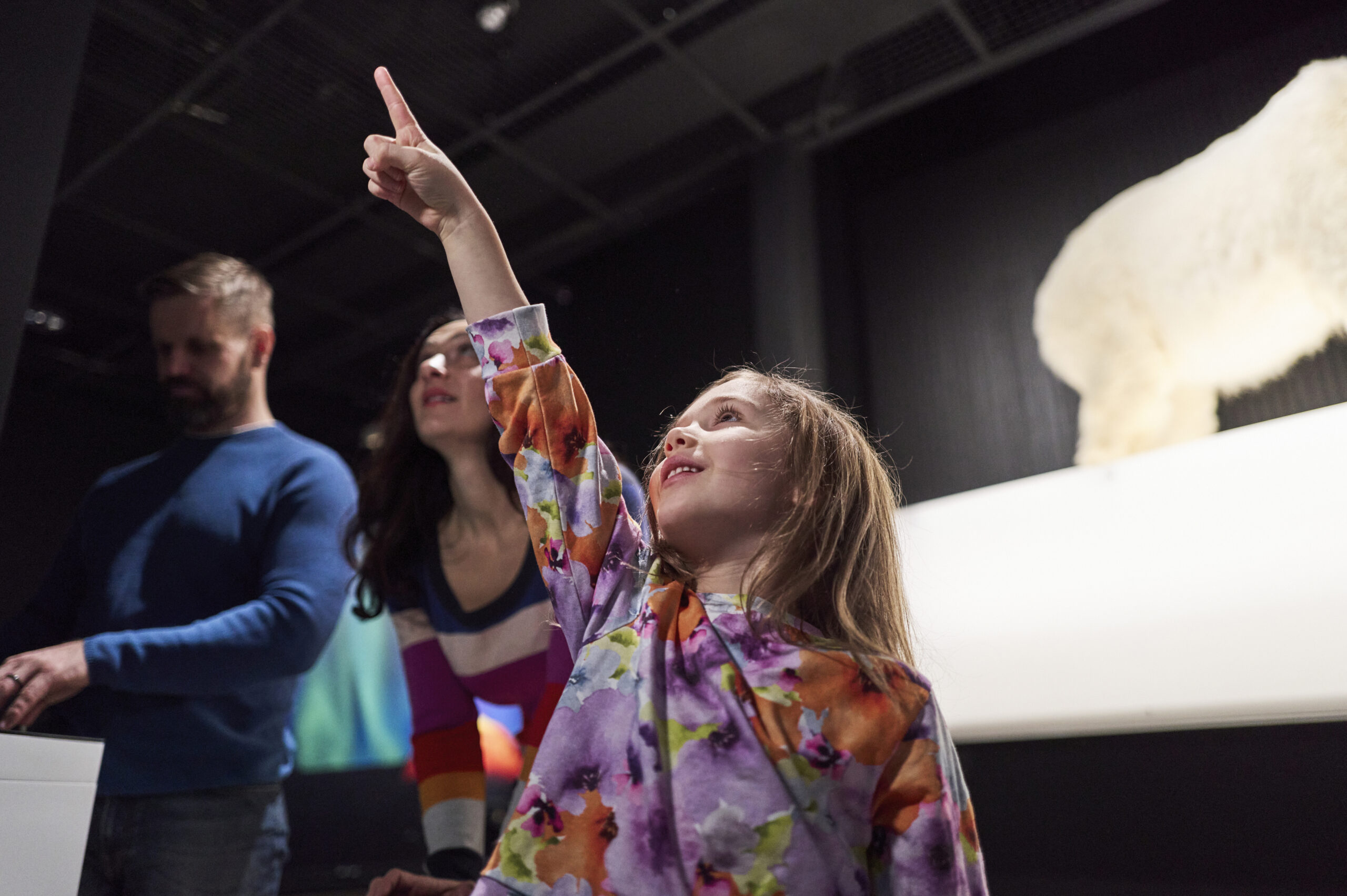 Lapsi osoittaa näyttelyssä esinettä.